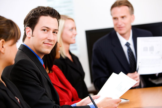 Business: Man In Meeting Looks At Camera