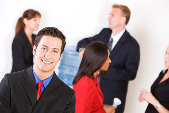 Business: Smiling Businessman with Group Around the Water Cooler