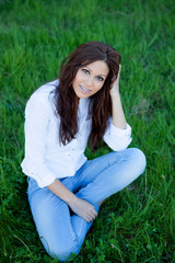 Brunette girl with brackets sitting on the grass