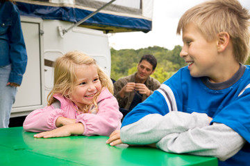 Camping: Kids Sit At Table Outside of Camper