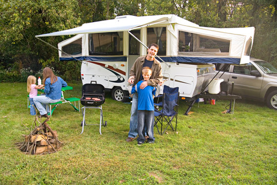 Camping: Boy Helps Father Cook Dinner On Grill By Camper