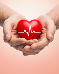 close up of hands holding heart with cardiogram