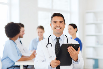Fototapeta premium happy doctor with clipboard over medical team