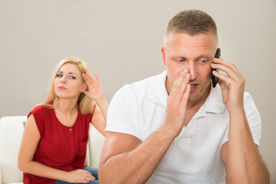 Wife Looking At Husband Talking On Mobile Phone