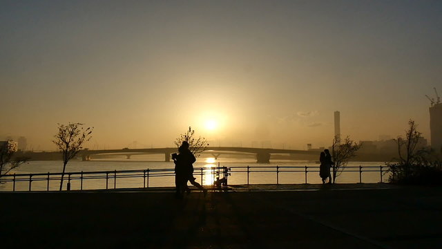 Slow motion sunset silhouette of people on the boardwalk.
