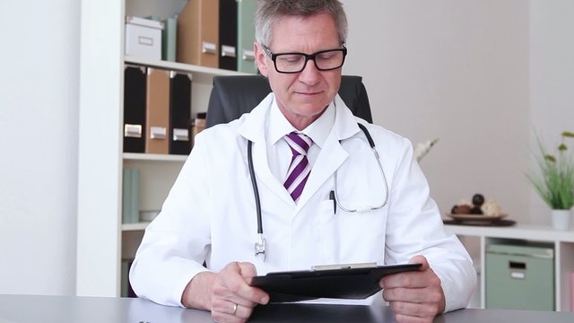 A male doctor sitting and giving a thumb up.