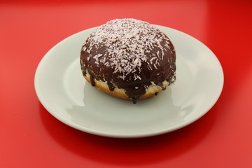 Single chocolate donut with sprinkled coconut pieces