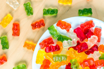 gummy bears on a white plate and wooden table