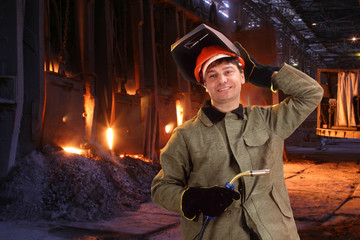Portrait of a happy male welder standing against the foundry