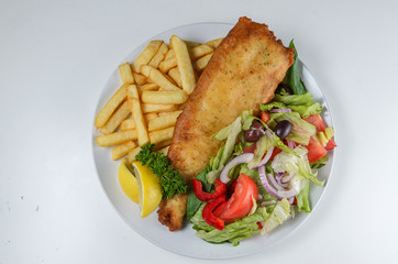 FIsh and chips serrved with salad on white plate