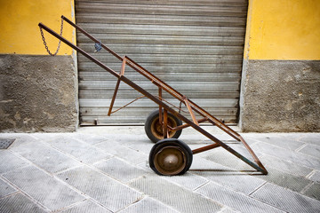 Old metal pushcart against a colored wall