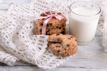 Tasty cookies and glass of milk on color wooden background