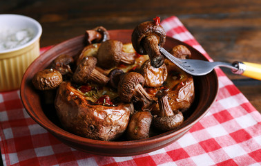 Baked potatoes with mushrooms in bowl and sauce