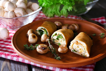 Pancakes with creamy mushrooms in plate on wooden table,