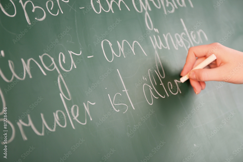 Wall mural Teacher hand writing grammar sentences on blackboard background