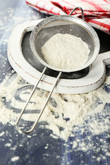 Obraz na płótnie Canvas Sifting flour through sieve on wooden table, closeup
