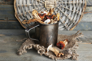 Dried mushrooms in metal cup on wooden background