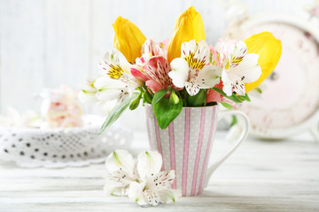 Fototapeta na wymiar Beautiful flowers in cup, on wooden background