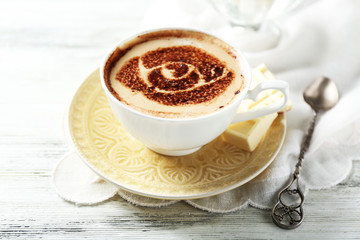 Cup of latte coffee art on wooden table, on light background
