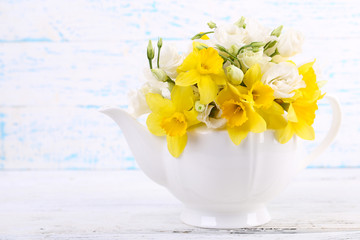 Beautiful bouquet of yellow daffodils and roses in teapot