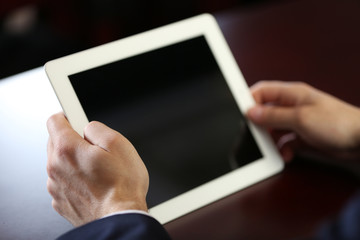 Businessman working with tablet at wooden table, closeup