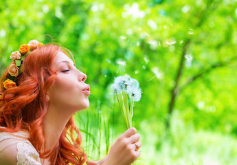 Pretty woman blowing on dandelion