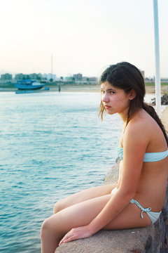preteen beautiful girl in swimming suit on the blue sea with yac