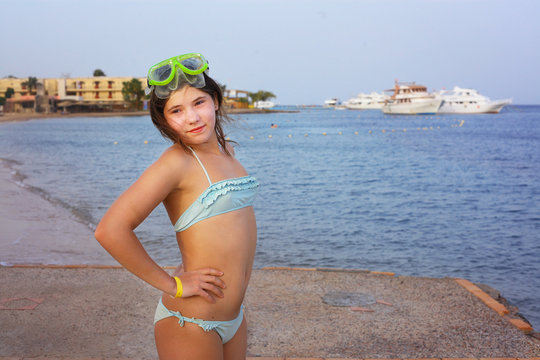 preteen girl in snorkeling mask on the blue sea with yacht backg