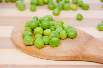 Wooden spoon with seeds of green peas