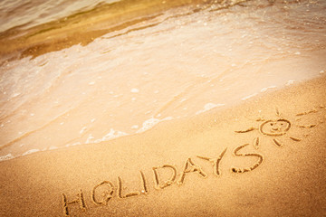 The word holidays written in the sand on a beach