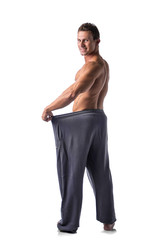 Fototapeta premium Shirtless young male bodybuilder has lost weight, wearing large