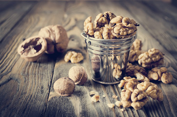 Walnut kernels and whole walnuts on wooden table