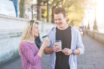 Young couple walking in London holding a cup of tea