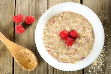 Breakfast oatmeal with raspberries on wood with spoon