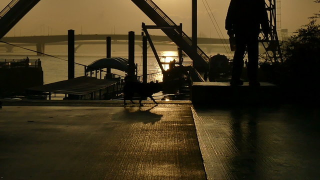 Slow motion sunset silhouette of people on the boardwalk.