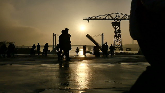 Slow motion sunset silhouette of people on the boardwalk.