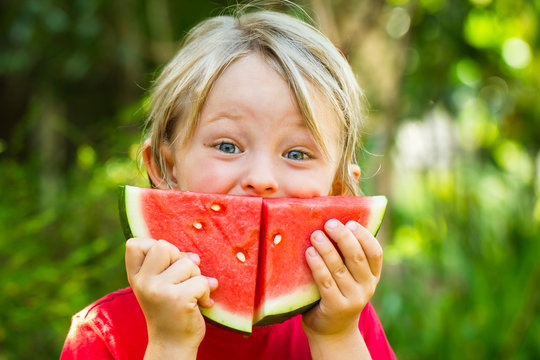 Funny happy child eating watermelon outdoors