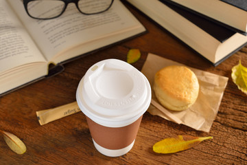 Paper cup of coffee and books on wooden table
