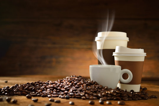 Cups of coffee and coffee beans on old wooden background