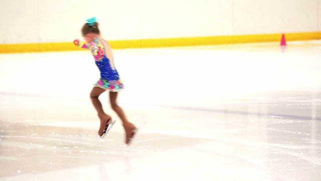 Young figure skater practicing at indoor skating rink.
