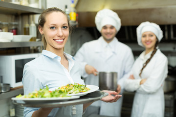 Chefs and waitress at kitchen