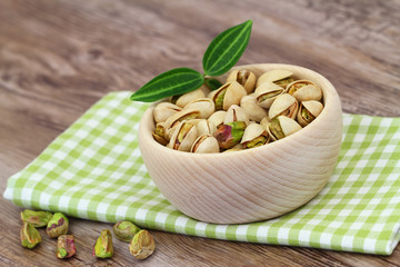 Pistachio nuts in wooden bowl on checkered cloth