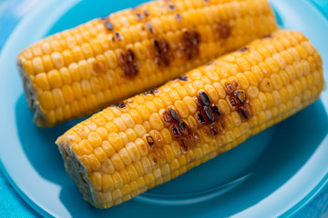 Glass plate with roasted sweet corn, close-up, selective focus