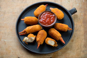 Frying pan with breaded crab claws and dip sauce, studio shot