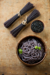 Noodles made of black rice, rustic wooden surface, above view