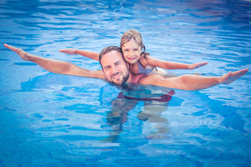 Fototapeta na wymiar Child and father playing in swimming pool