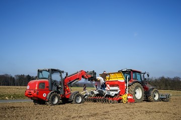 Obraz premium Ackerbau, Landwirt mit Hoftrak füllt Saatgut in Sämaschine