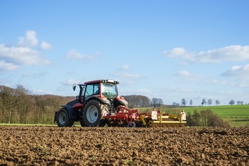 Obraz premium Roter Schlepper mit Grubber, von der Seite