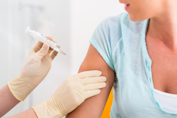 Frau beim Arzt erhält Impfung per Spritze