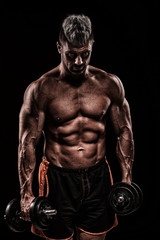 Obraz na płótnie Canvas muscular young man lifting weights on dark background